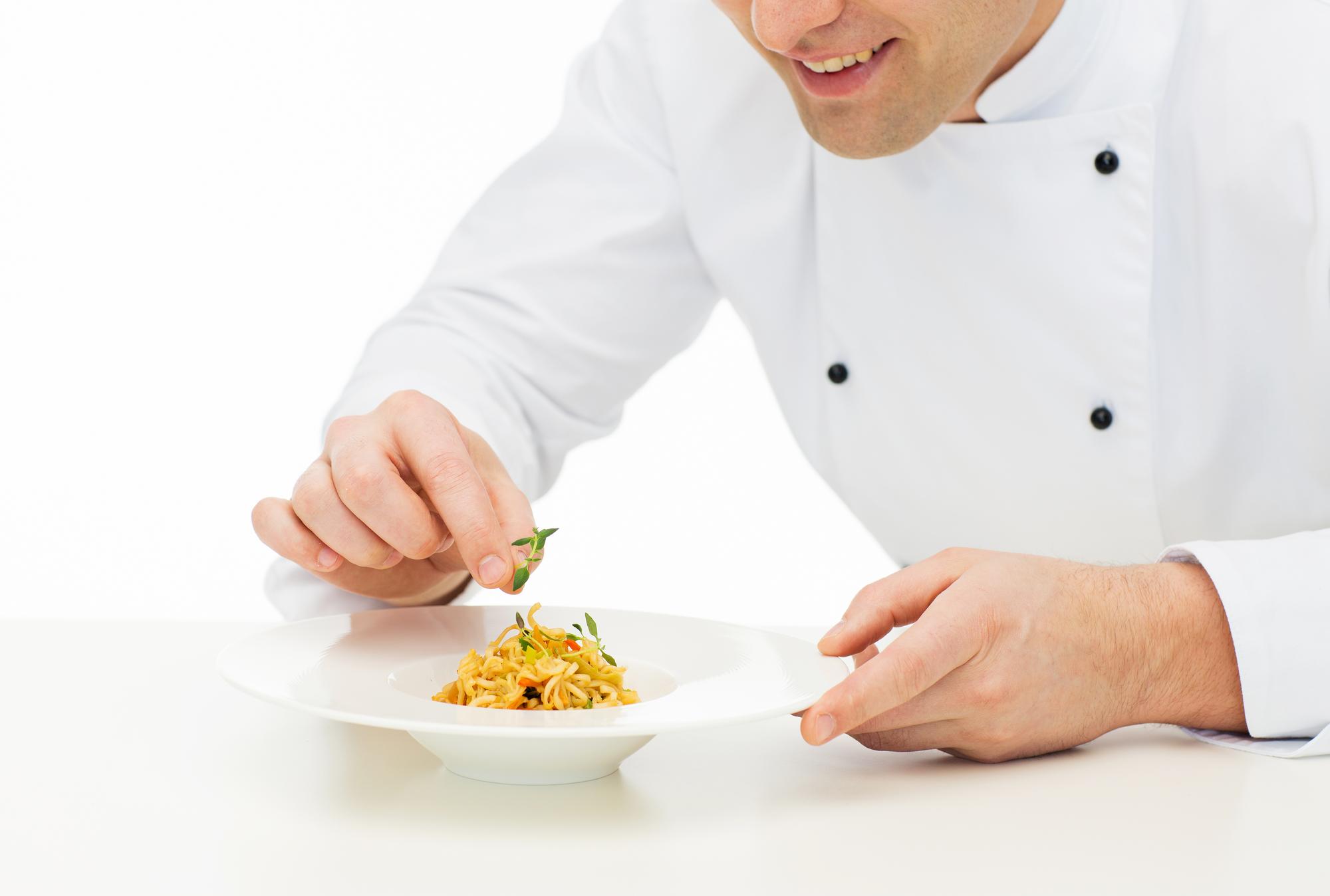 Close-up of hands plating a dish during an online class
